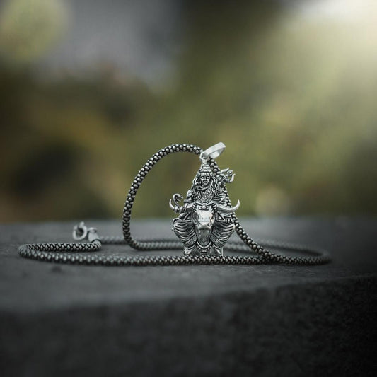Lord Shiva silver pendant on a chain displayed against a natural background
