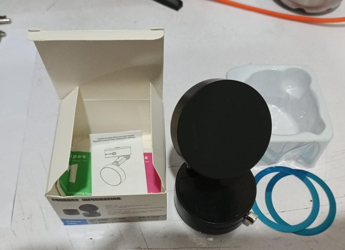Magnetic car dashboard phone holder in black with packaging and installation accessories on table
