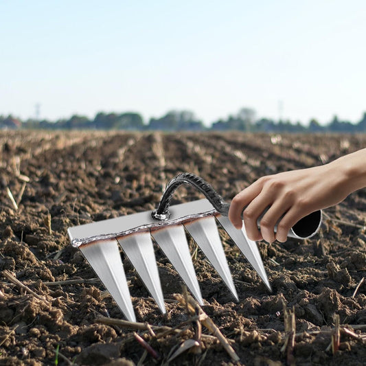 Manual soil cultivator for gardeners held by hand with sharp metal tines tilling soil in field