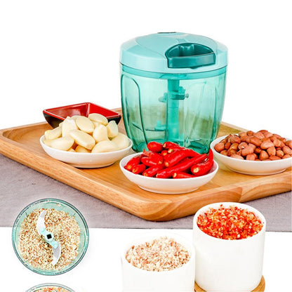 Manual stainless steel vegetable chopper with bowls of chopped garlic, chilies, and peanuts on a wooden tray