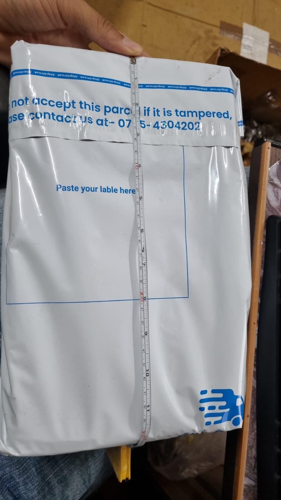White sealed package held in hand secured with measuring tape for mini weeder pack for raised beds