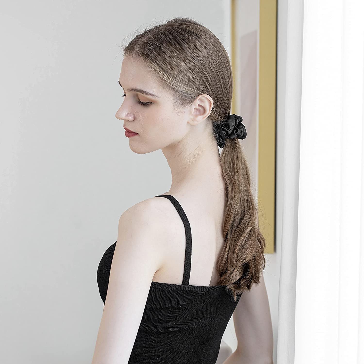 Woman with long brown hair wearing a black mulberry silk elastic band for hair holding a ponytail