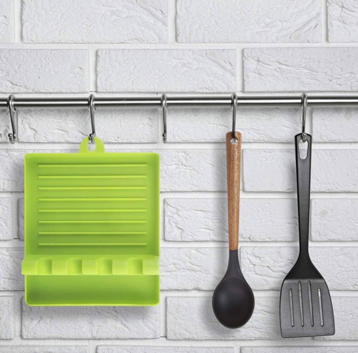 Bright green multi-functional spatula holder hanging on a kitchen wall with other utensils