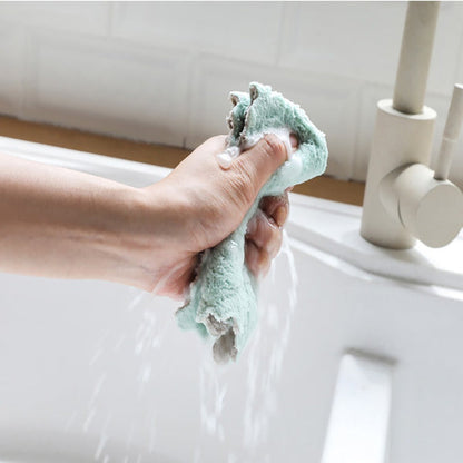 Hand squeezing a damp multi-purpose kitchen wash towel in a clean sink for efficient cleaning