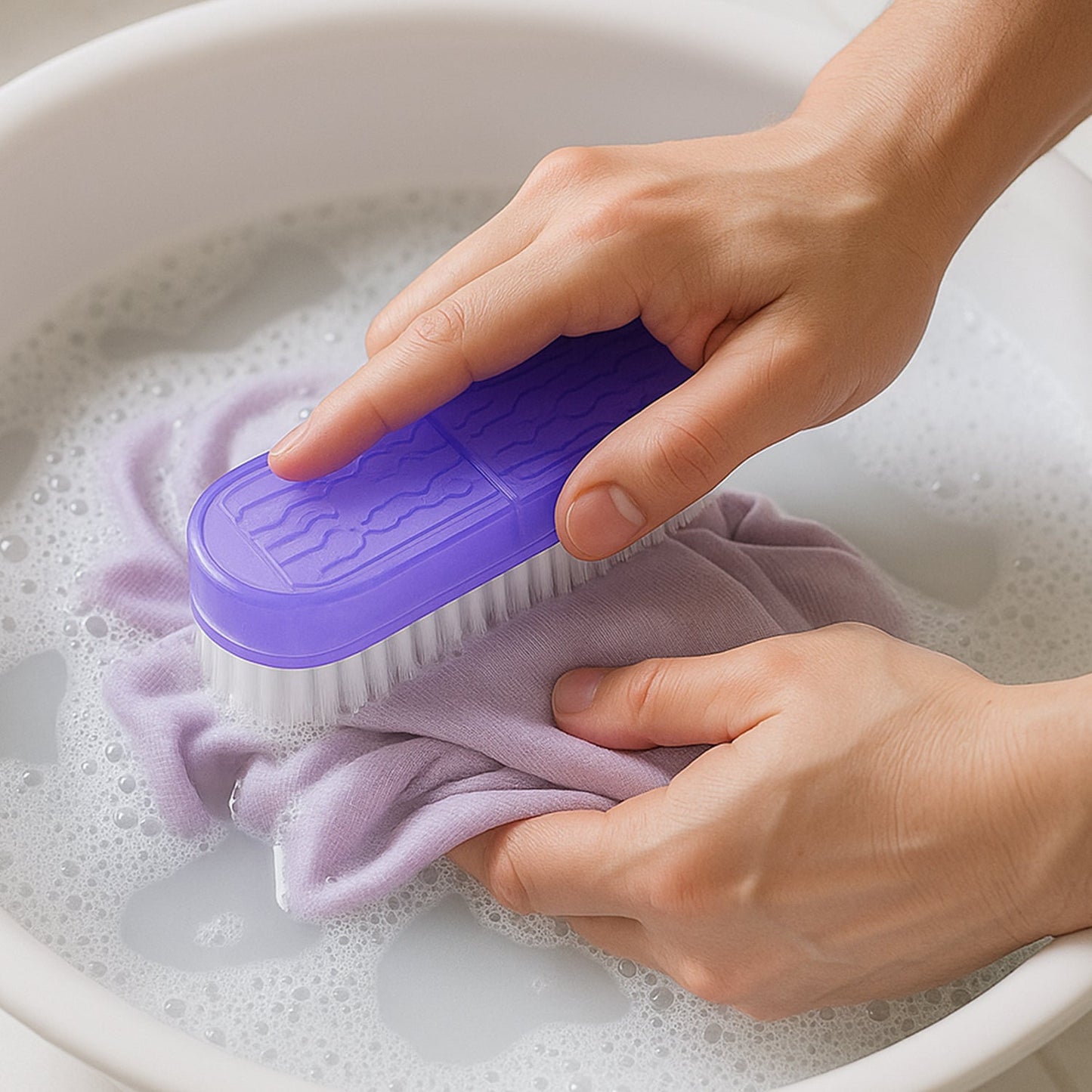 Person using a multipurpose laundry brush to scrub a purple cloth in soapy water