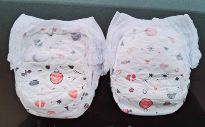 Two natural disposable diapers for babies with playful red and gray patterns, perfect for all-day comfort