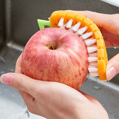 Hands using a non-toxic vegetable scrubbing brush on a fresh red apple in a sink