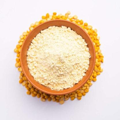 Bowl of organic besan flour surrounded by raw chickpeas for healthy cooking