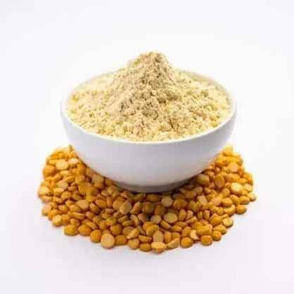 Organic besan flour in a white bowl surrounded by yellow split chickpeas, ideal for baking and cooking