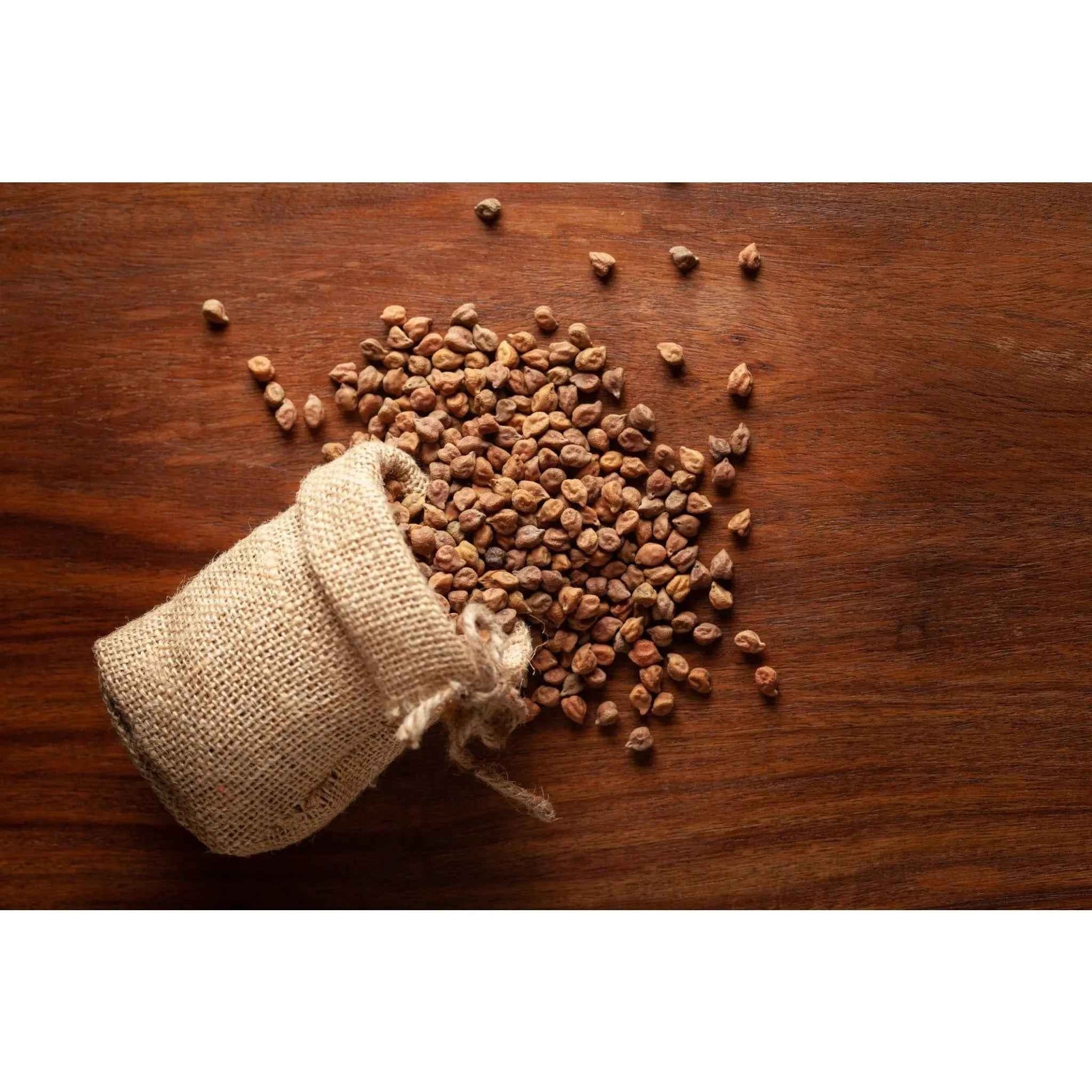 Organic black desi channa spilled from a burlap sack on a wooden surface, perfect for cooking and snacks
