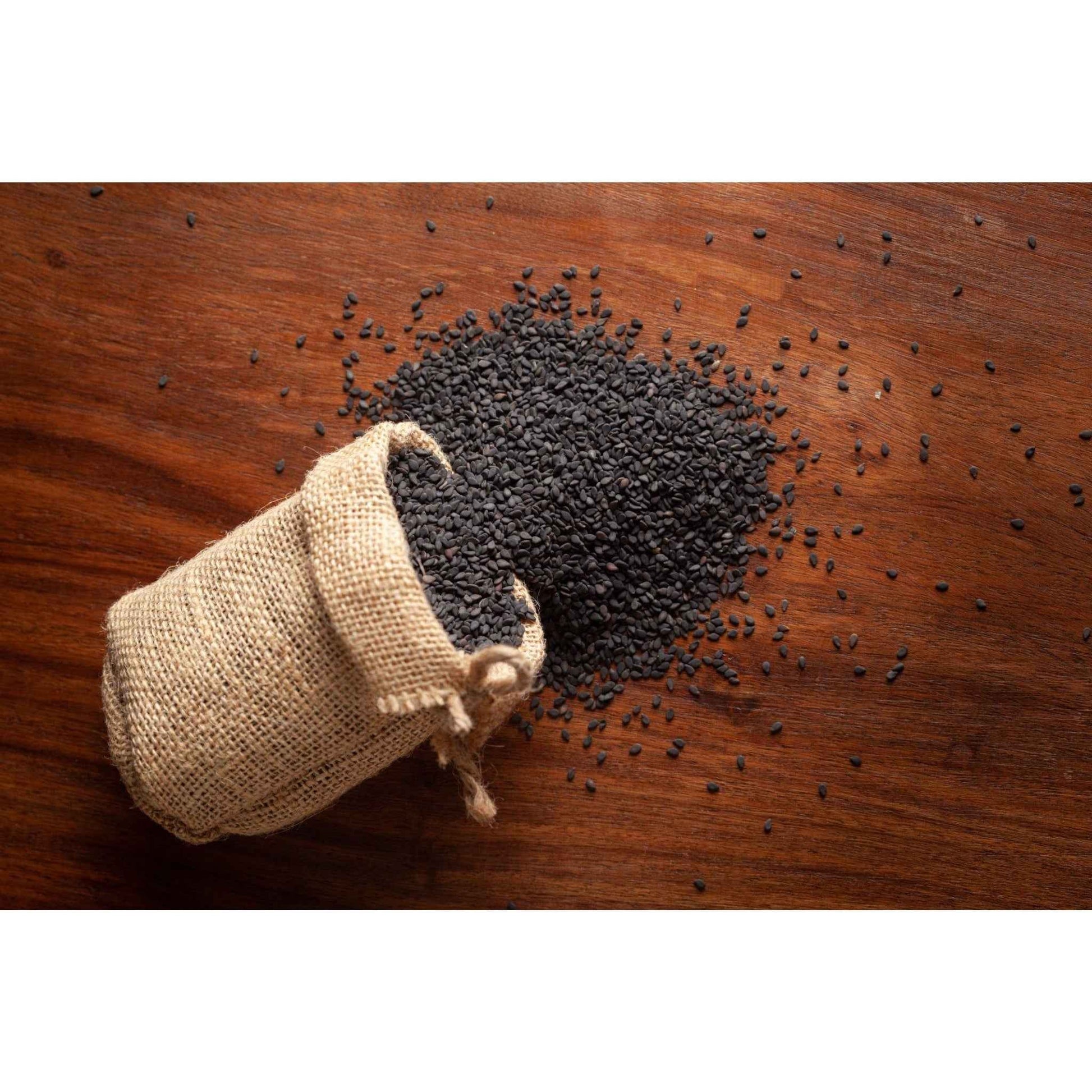 Organic Black Sesame Seeds spilling from a burlap sack on a wooden surface, perfect for cooking and nutrition.