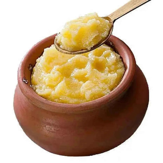 Natural yellow organic ghee butter in a clay pot with a wooden spoon for cooking and baking