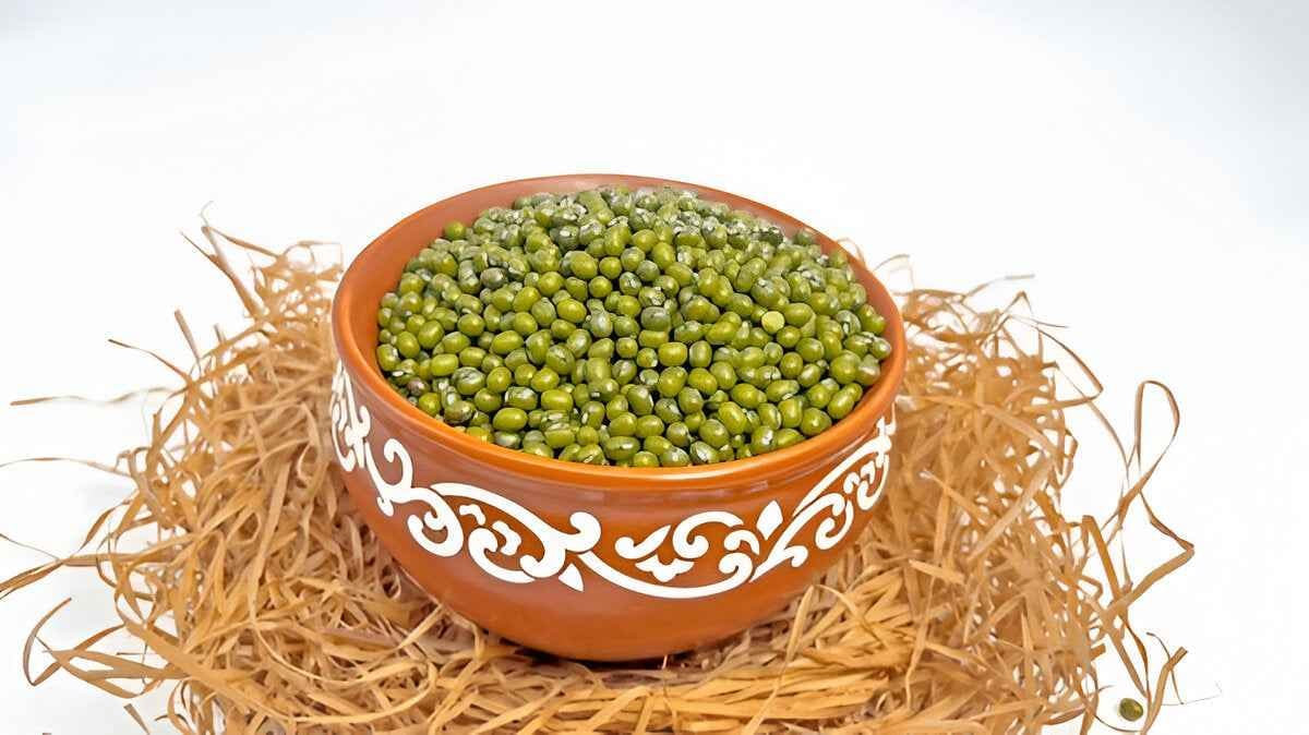 Bowl of organic green moong beans in a decorative clay pot, ideal for soups and salads