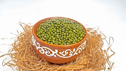 Bowl of organic green moong beans in a decorative clay pot, ideal for soups and salads