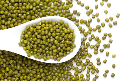 Organic green moong beans in a white spoon, perfect for healthy soups and salads