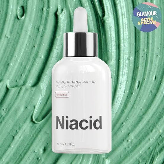 Organic niacid face serum in a glass dropper bottle against a green cream background