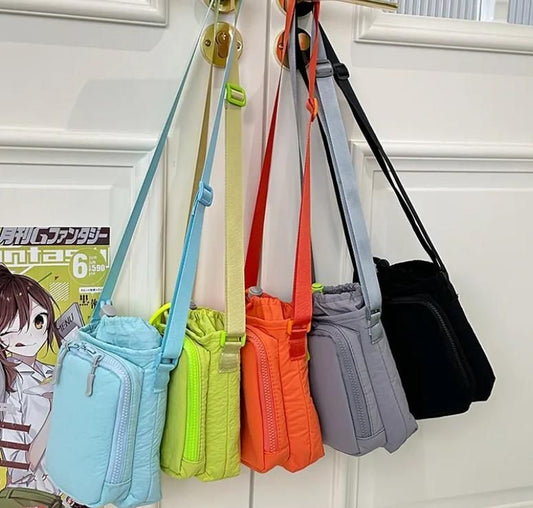 Colorful collection of organic side sling pouches hanging on a door, featuring various vibrant shades