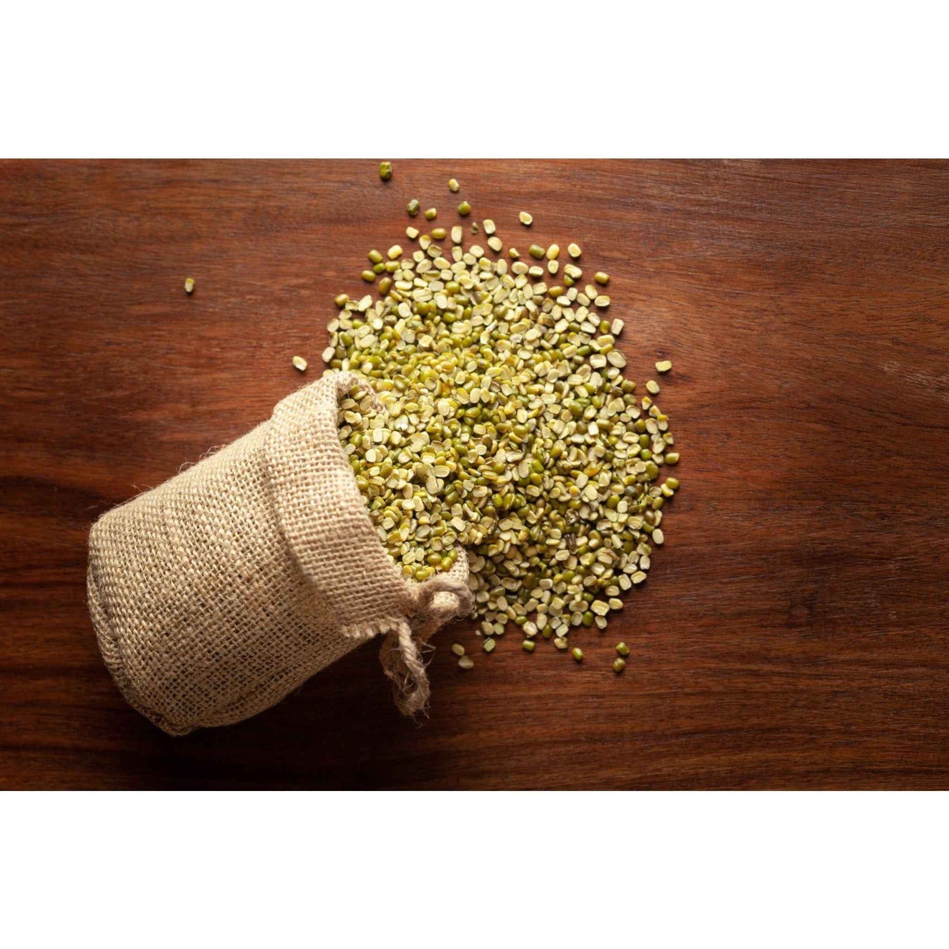 Brown burlap sack spilling organic split moong dal on a wooden surface, perfect for healthy meals