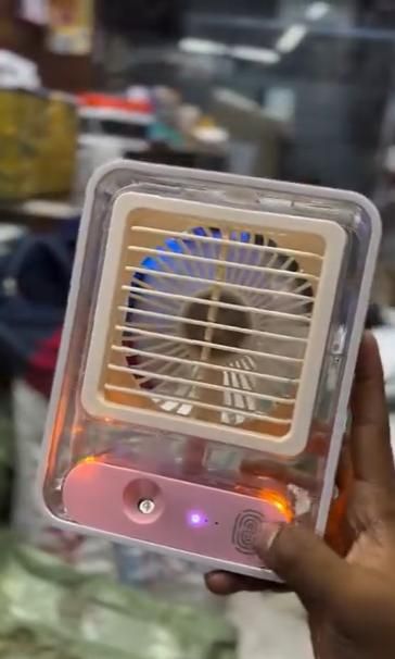 Portable personal cooling fan with water spray in clear casing, perfect for hot days and outdoor use