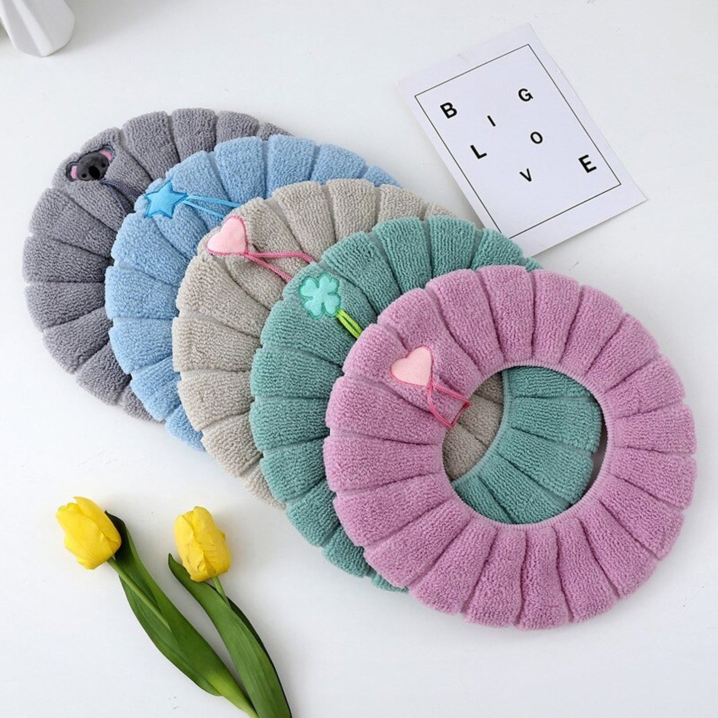 Five colorful plush toilet seat covers in purple, teal, gray, blue, and pink for added comfort
