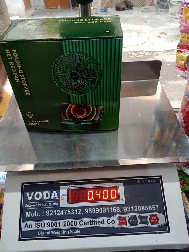 Powerful rechargeable table fan in green packaging displayed on a weighing scale