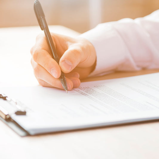 Person writing on a premium transparent exam pad with a pen on a clipboard