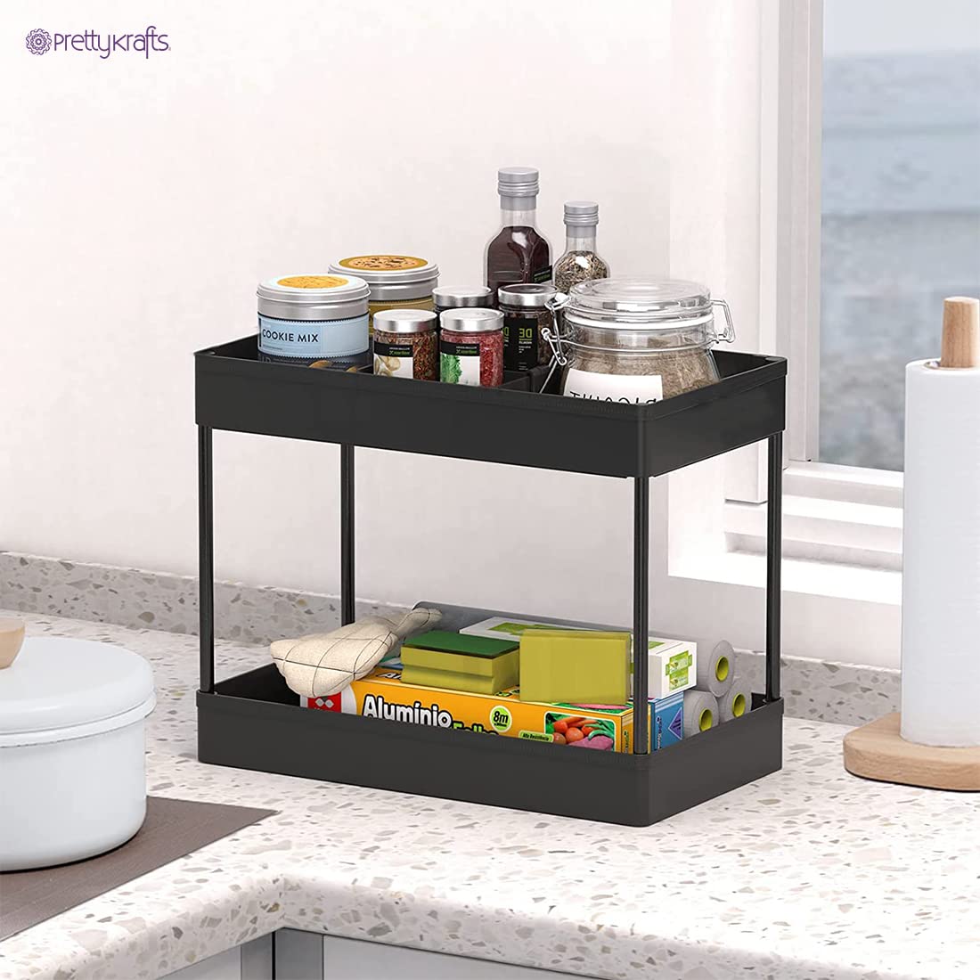 Black multipurpose plastic rack with wheels holding jars and kitchen supplies on a countertop