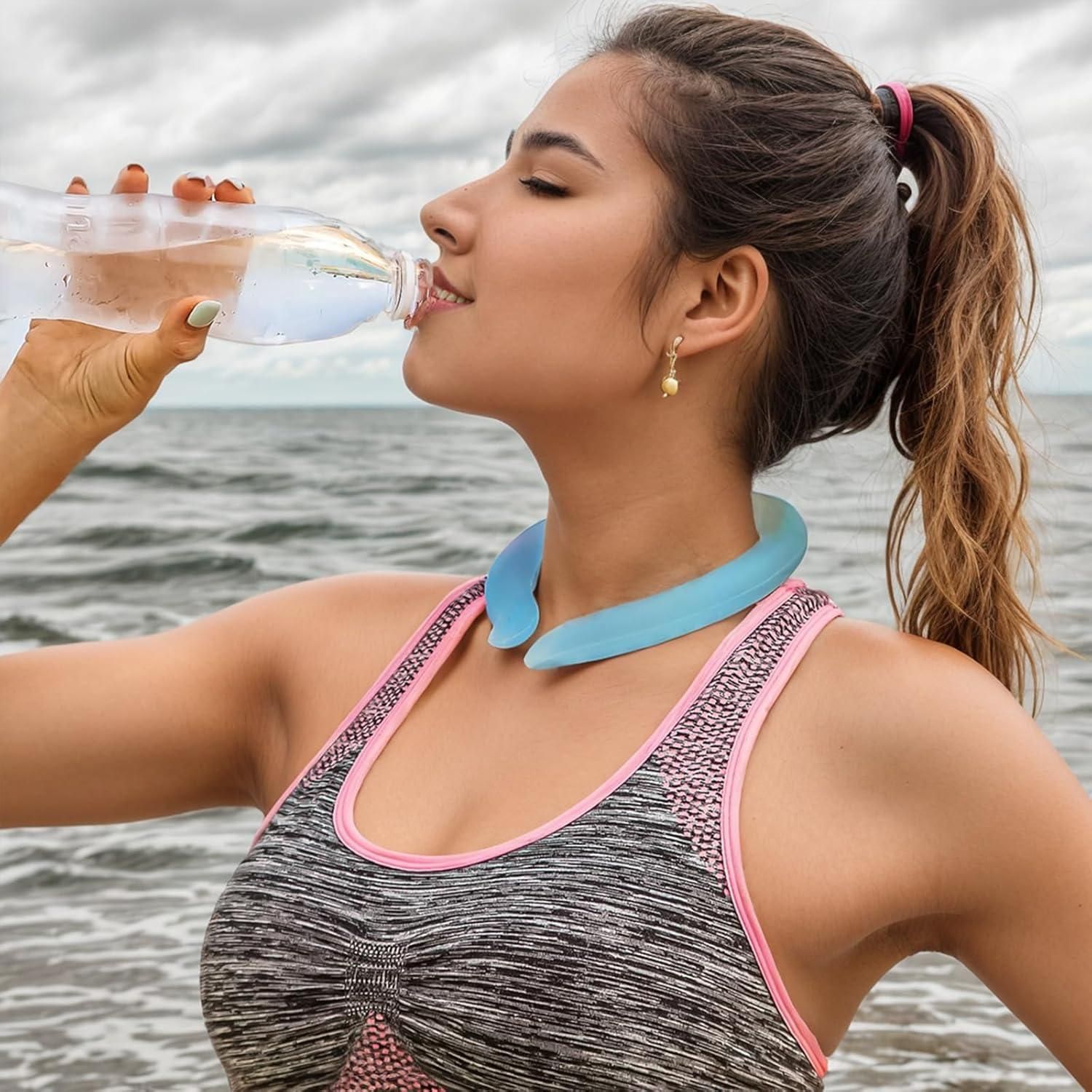 Woman sipping water while wearing a reusable neck cooling wrap on the beach for hot weather relief