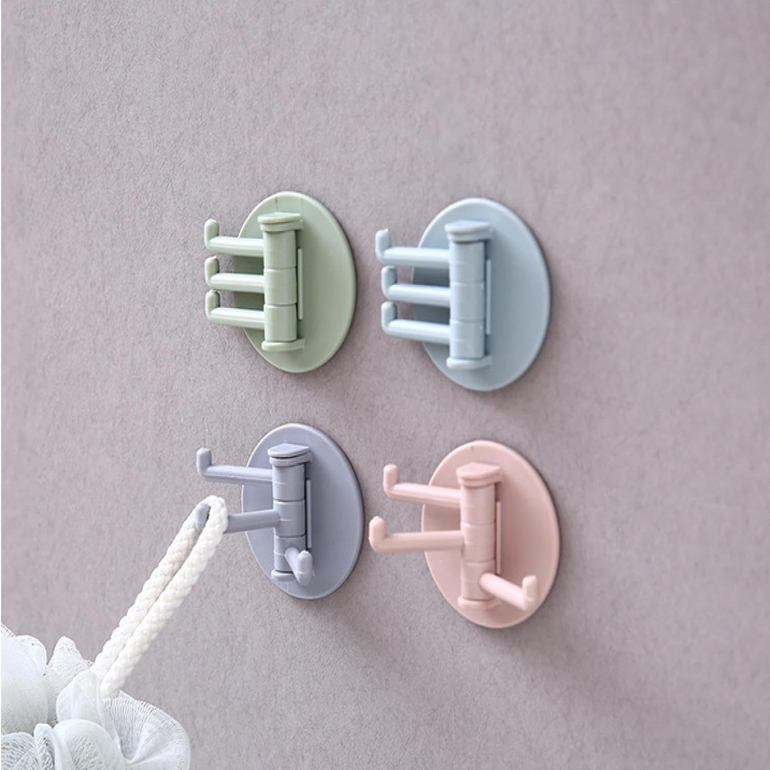 Set of four rotating sticky wall hooks in pastel colors for versatile home organization