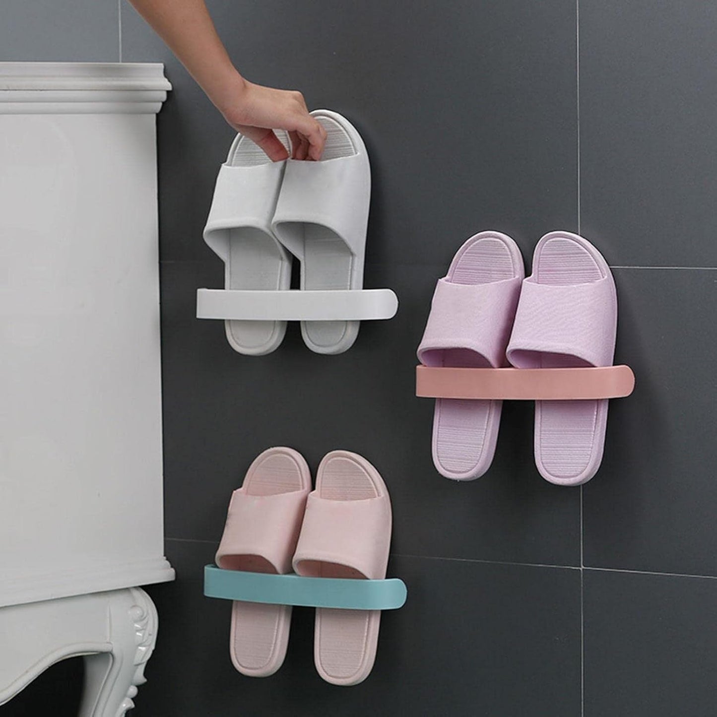 Self adhesive bathroom towel rack holding stylish bathroom slippers in pastel colors on a tiled wall