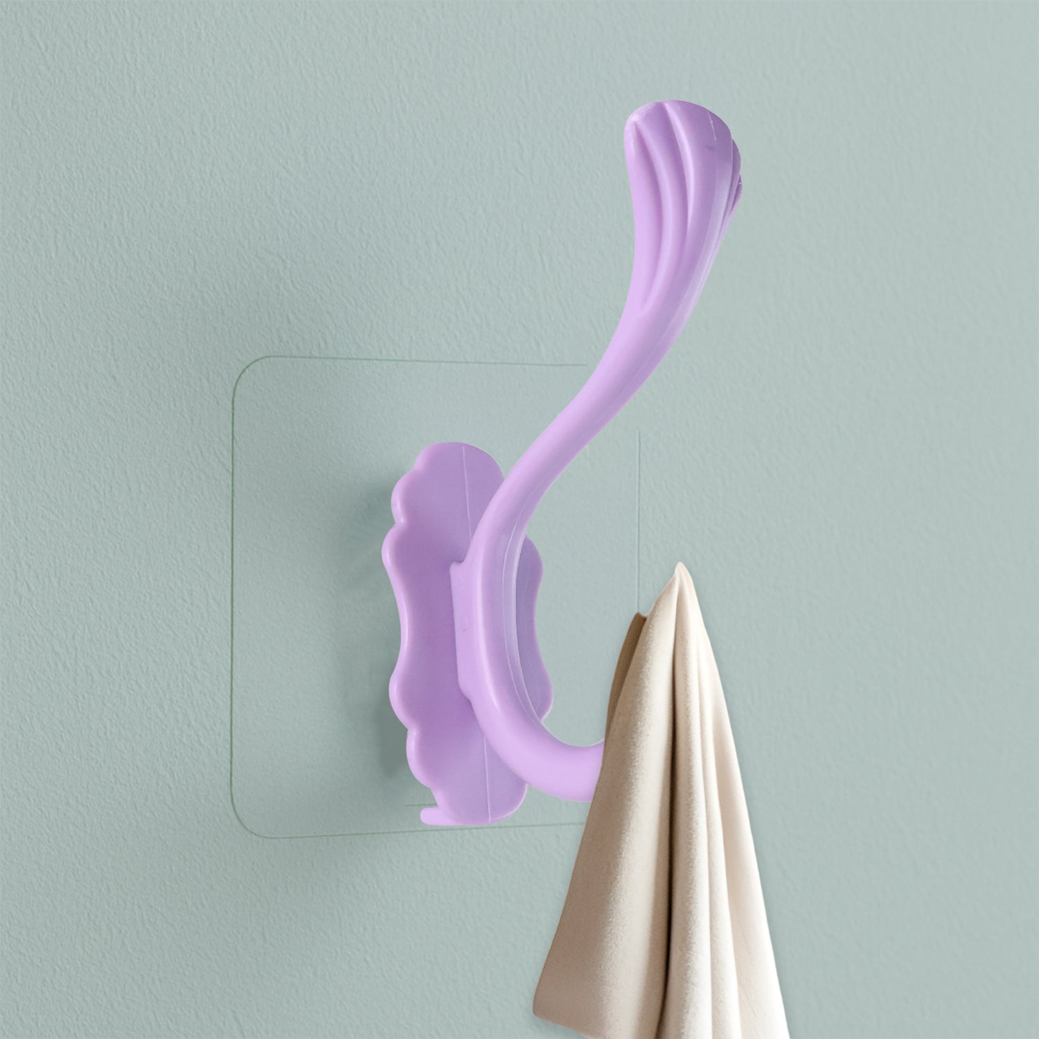 Self-adhesive heavy duty wall hook in purple holding a towel on a light green wall