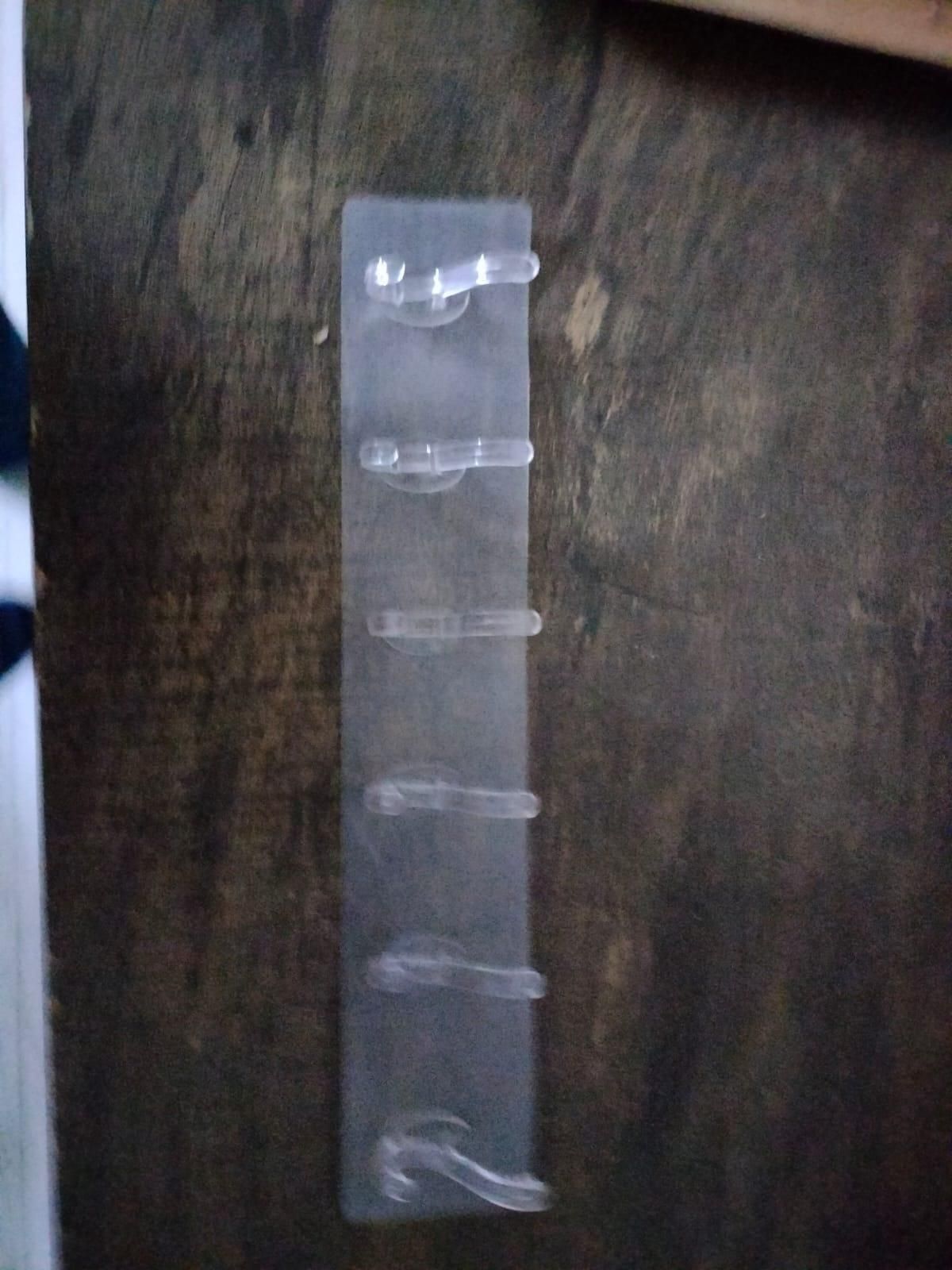 Clear plastic self adhesive wall hanger hooks mounted on a dark wooden surface