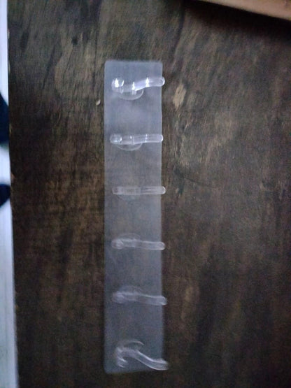 Clear plastic self adhesive wall hanger hooks mounted on a dark wooden surface