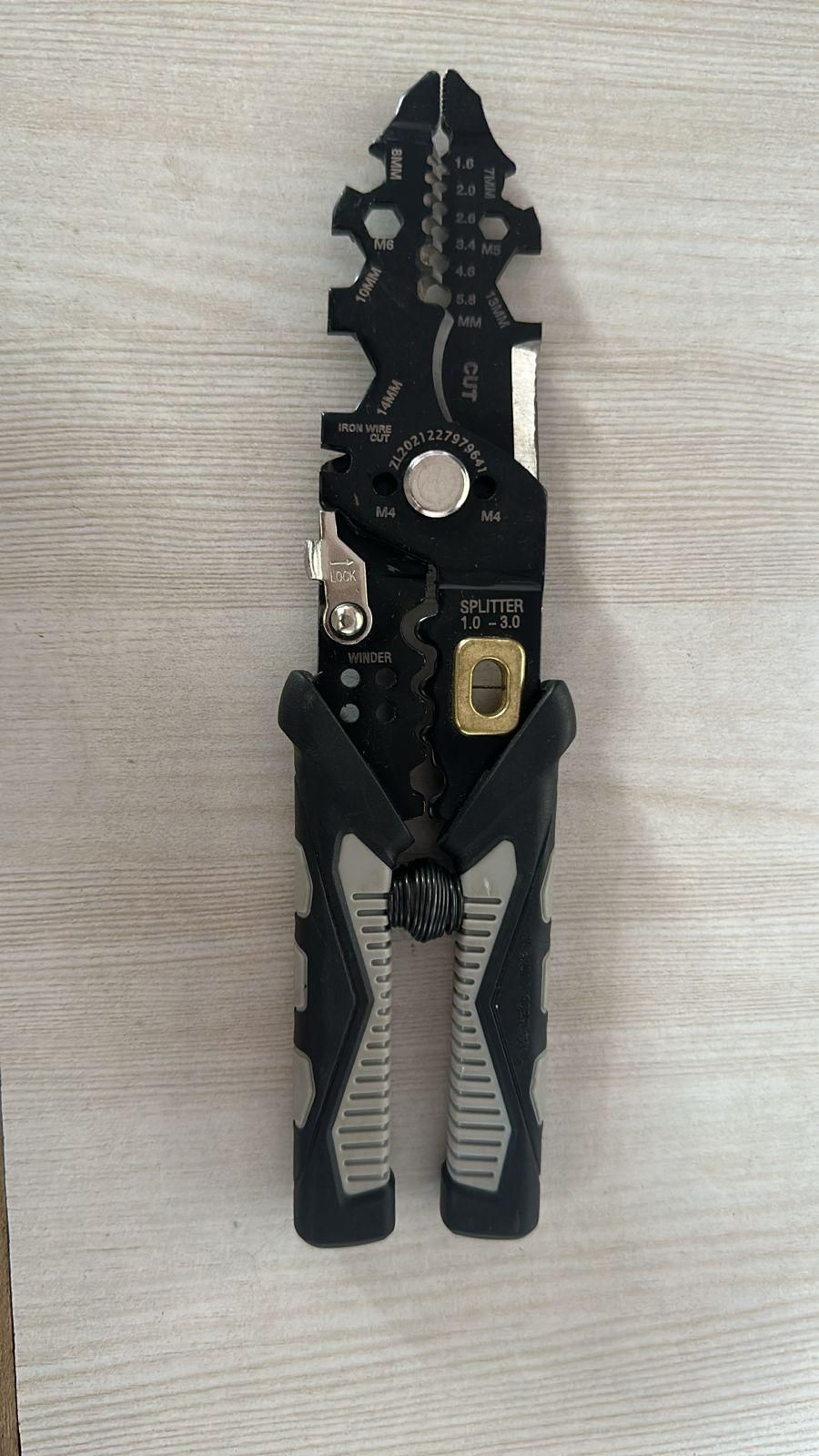 THE GIR FARMER multifunctional wire stripper tool with black ergonomic handles on wooden surface