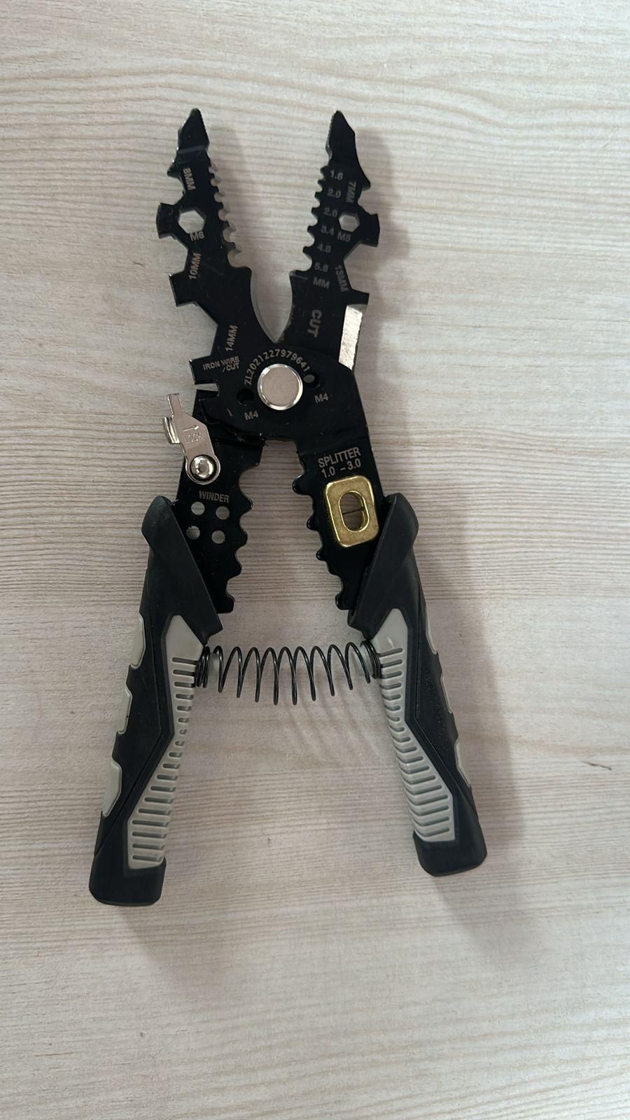 THE GIR FARMER multifunctional wire stripper tool with ergonomic black and gray handles on wooden surface