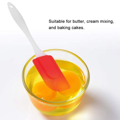 Red and white silicone baking spatula in a bowl for mixing butter and cream