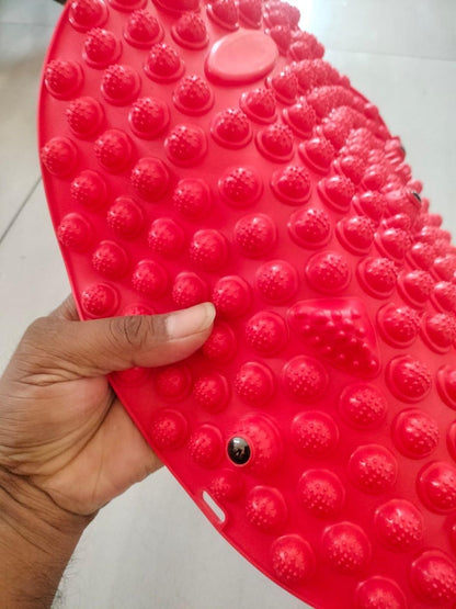 Hand holding red silicone foot massage pad with textured nodules for improved foot comfort