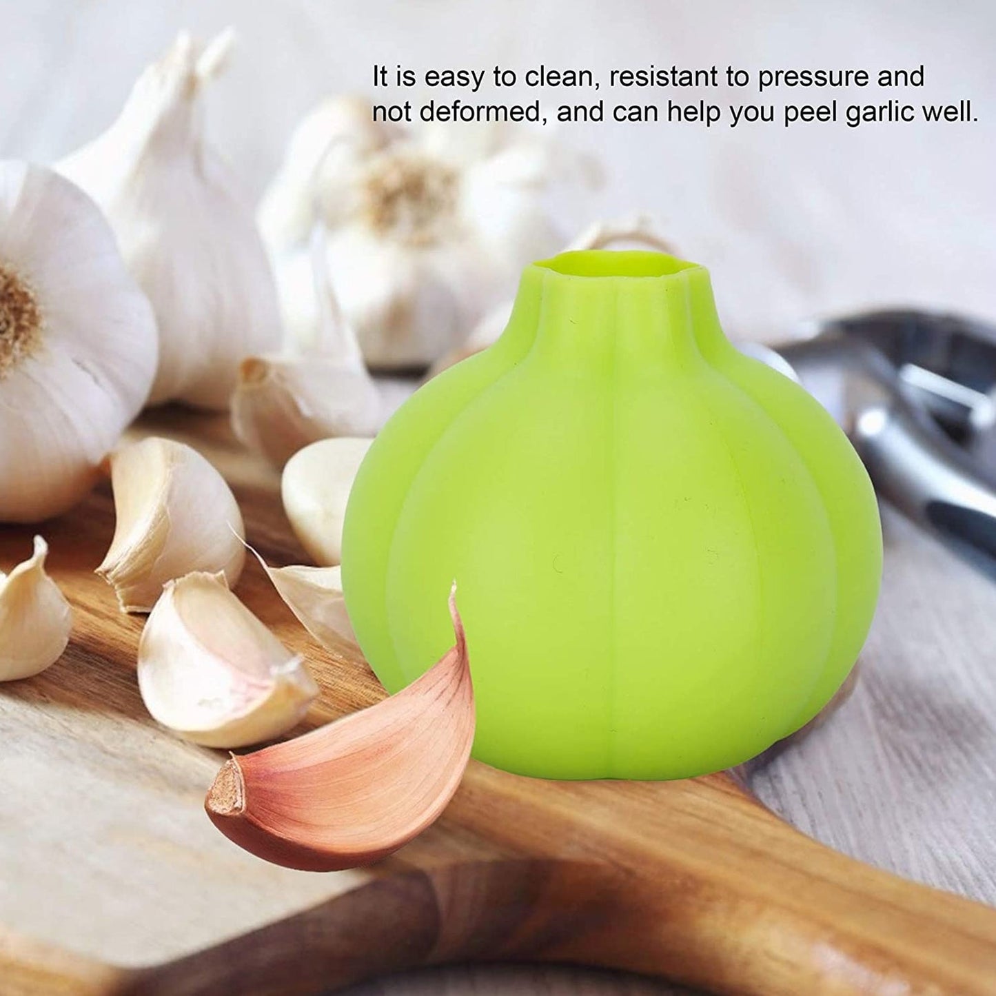 Silicone garlic peeler in green sitting on a wooden cutting board with garlic cloves