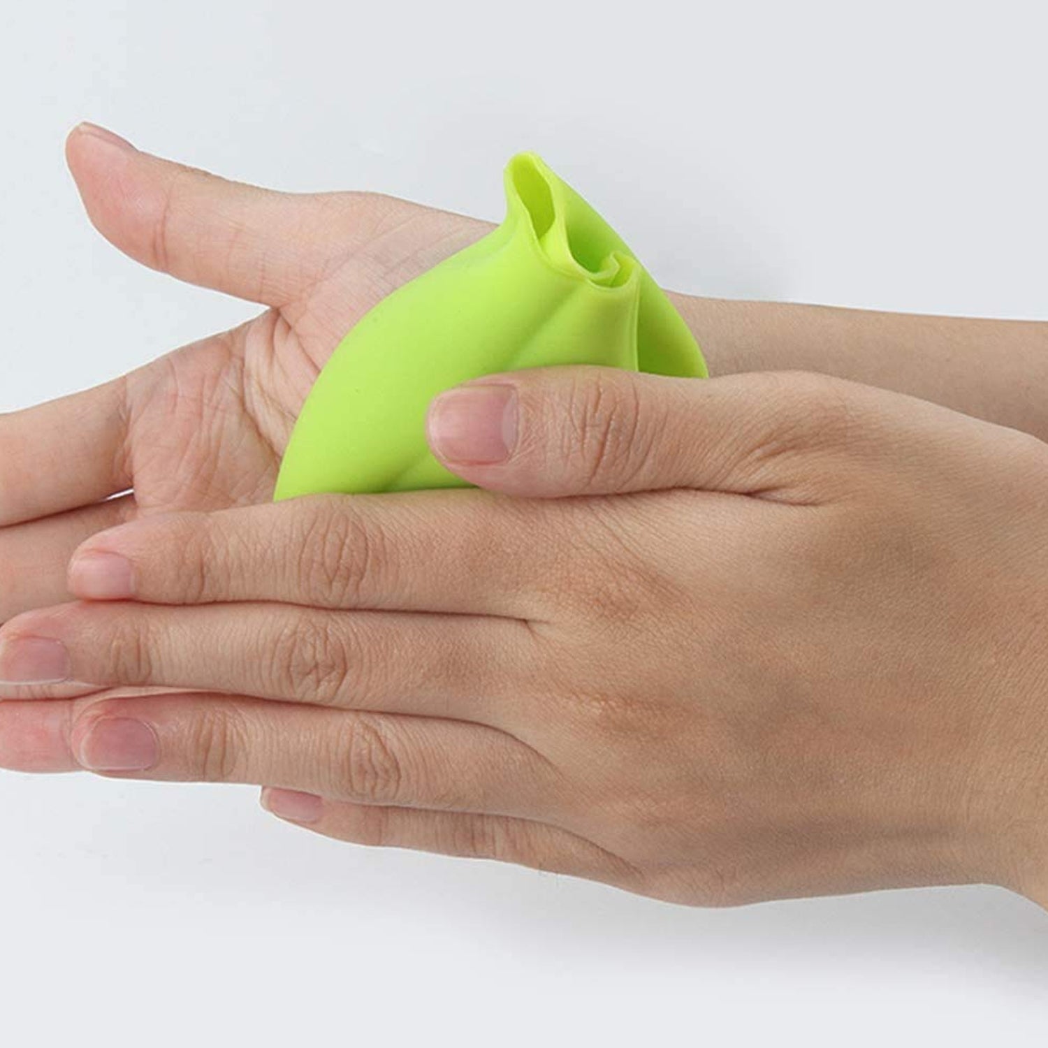 Green silicone garlic peeler being used to easily remove garlic skins at home