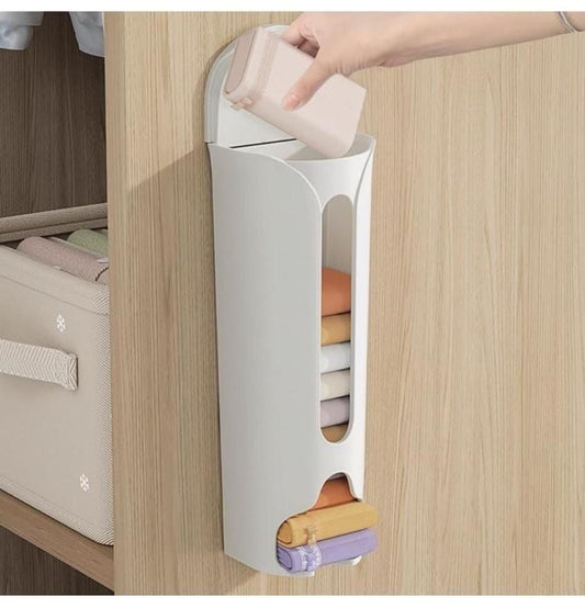 THE GIR FARMER white space saving wall storage mounted on wood wall holding folded cloths and a hand placing an item inside