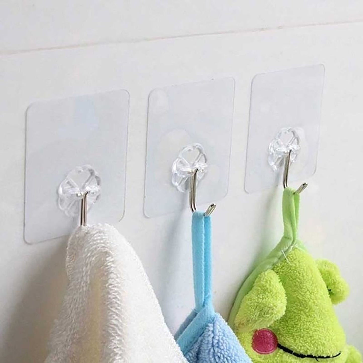 Transparent adhesive wall hooks holding towels, featuring stainless steel hooks for durability
