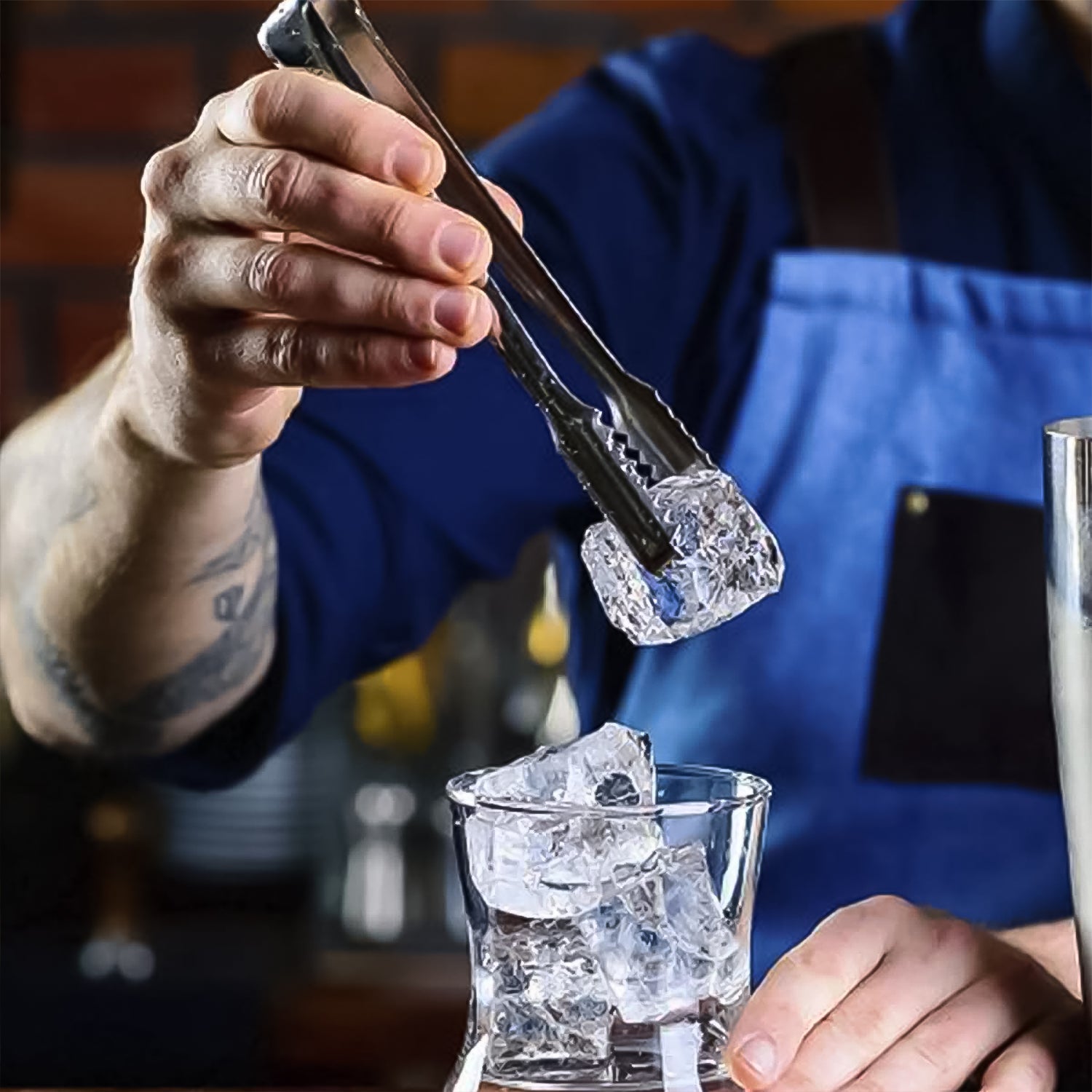Your Brand stainless steel ice cube tong in use to pick up ice cubes for drinks