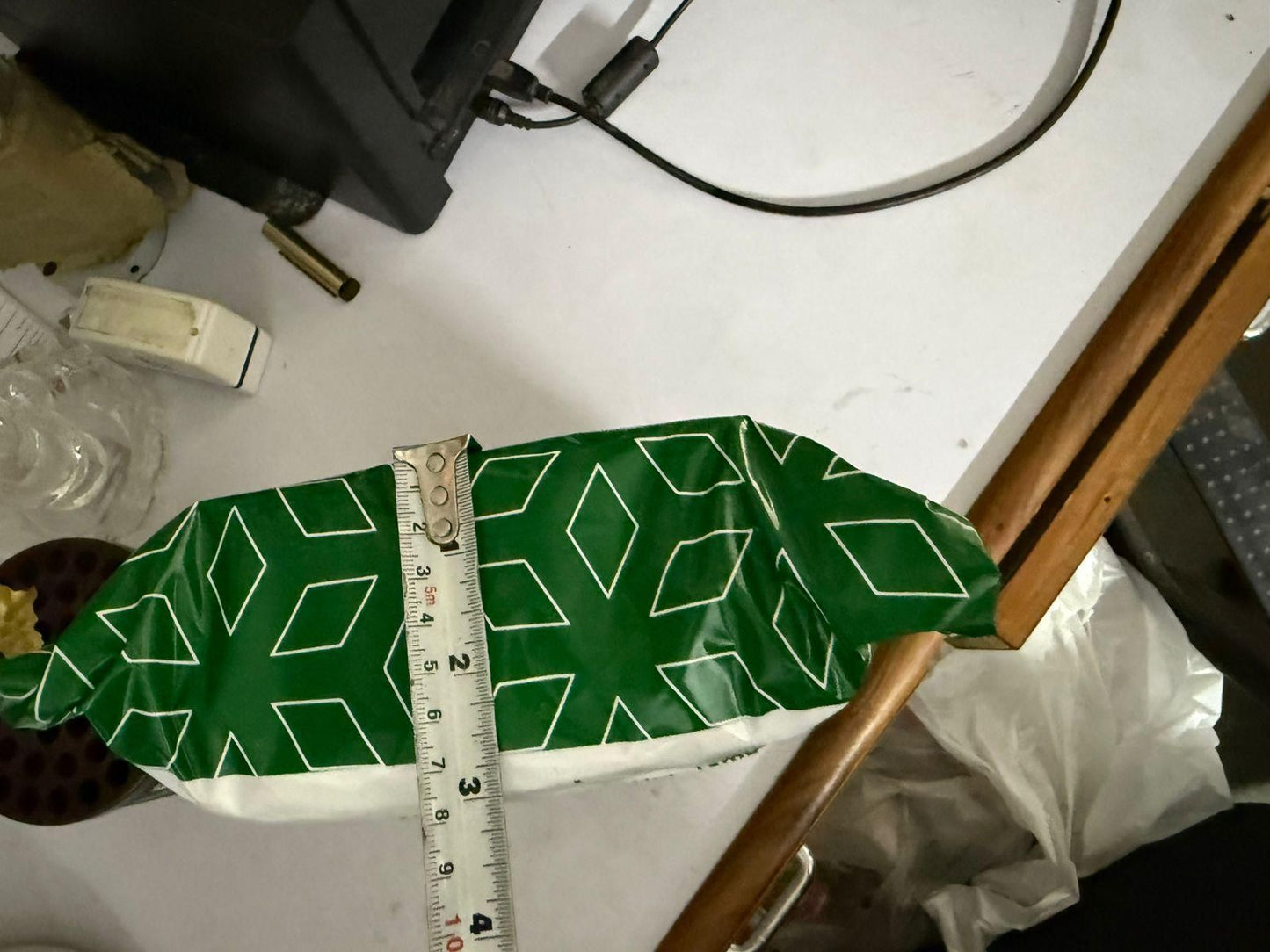 Green packaging of a stainless steel pet grooming glove on a table with measuring tape for size reference
