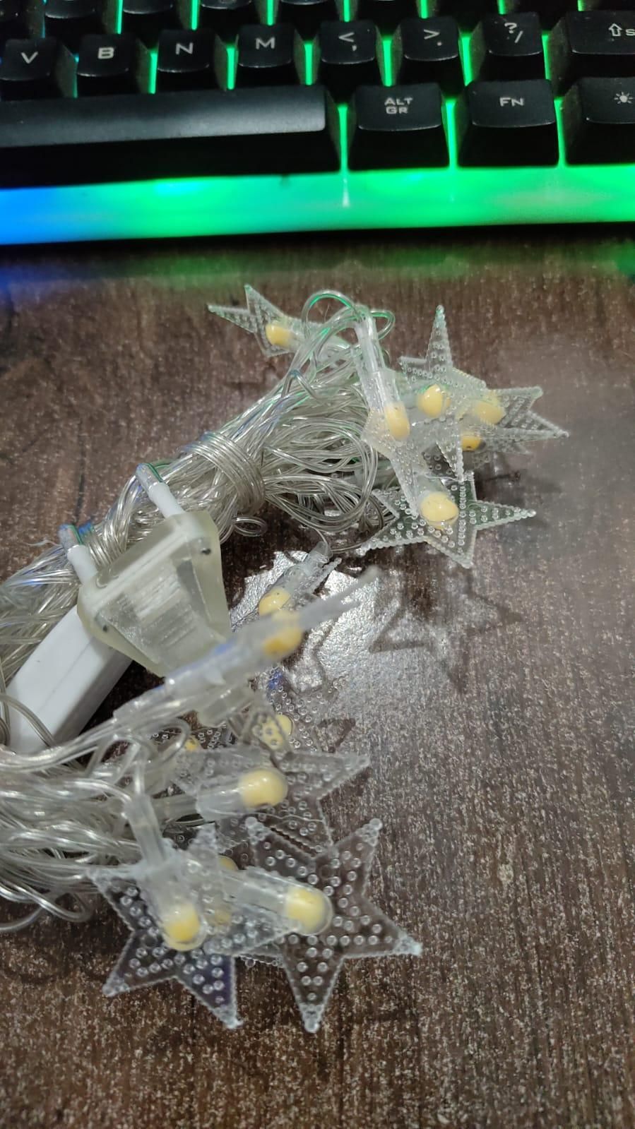 Twinkling star string lights for decoration on a wooden surface with a keyboard in the background