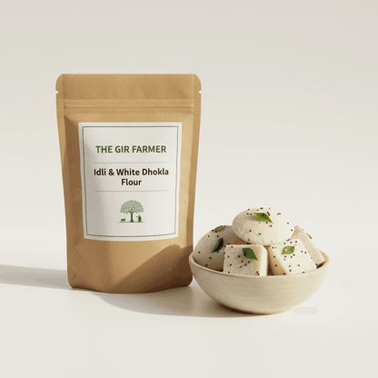 THE GIR FARMER Organic Idli & White Dhokla Flour in eco-friendly packaging with a bowl of soft dhokla.