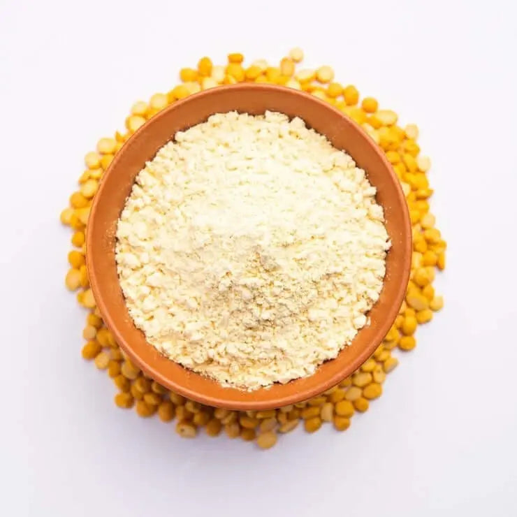 Organic besan flour in a bowl surrounded by chickpeas, perfect for healthy cooking