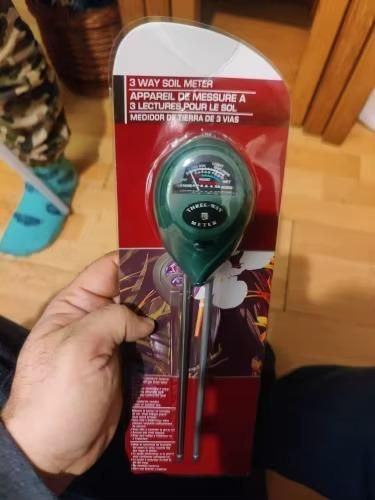Hand holding 3 way soil meter in packaging, best soil meter for home gardening with easy-to-read dial