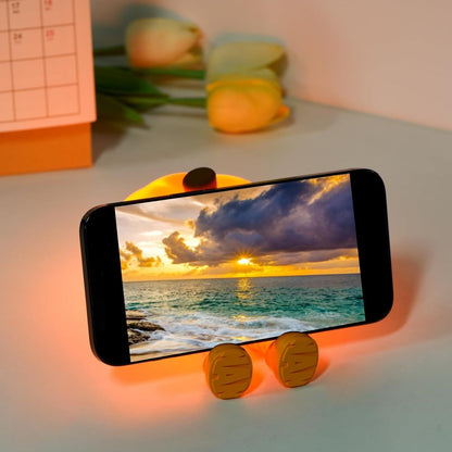 THE GIR FARMER touch control silicone lamp glowing orange holding smartphone on desk with flowers
