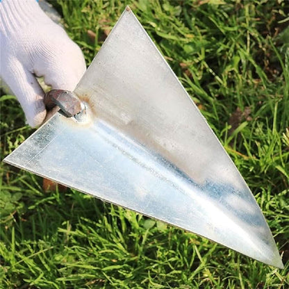 Hand holding a triangle weed remover tool with metal blade over green grass background