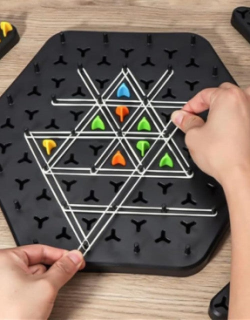 Hands setting up the Triggle board game with colorful pegs on a black hexagonal board